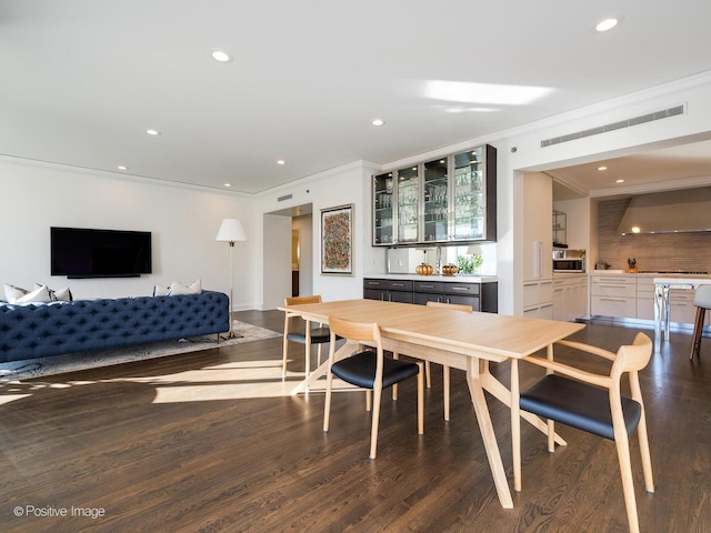 dining space featuring bar area, dark hardwood / wood-style floors, and ornamental molding