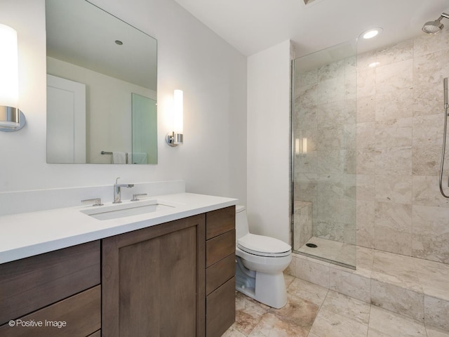 bathroom with toilet, vanity, and a tile shower