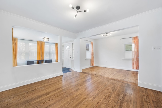 empty room with hardwood / wood-style floors, a wealth of natural light, and ornamental molding