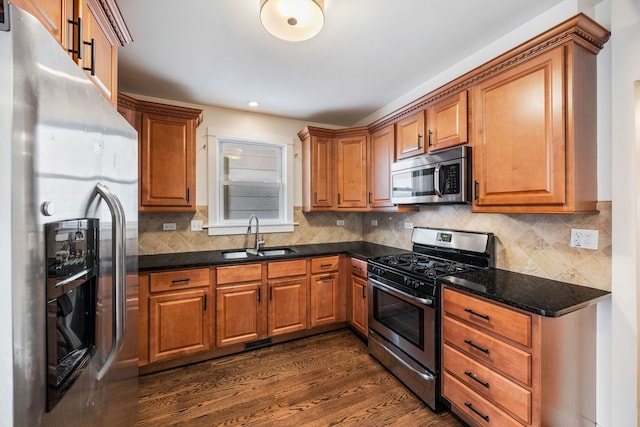 kitchen featuring sink, dark stone countertops, appliances with stainless steel finishes, dark hardwood / wood-style floors, and backsplash