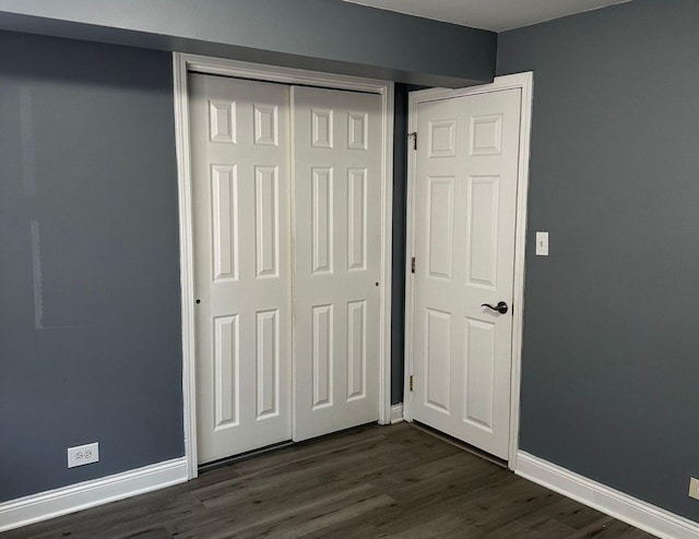 unfurnished bedroom with a closet and dark hardwood / wood-style floors