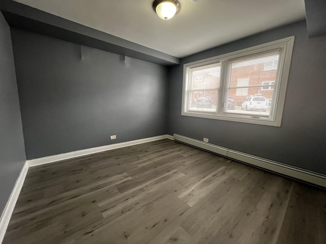 empty room with a baseboard heating unit and hardwood / wood-style floors