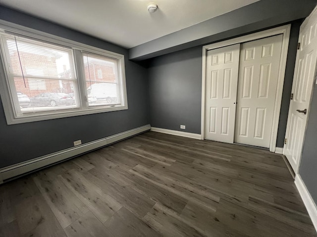 unfurnished bedroom with a closet, dark hardwood / wood-style flooring, and a baseboard radiator