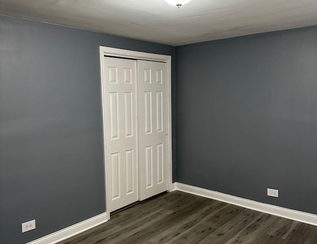 unfurnished bedroom with a closet and dark hardwood / wood-style flooring