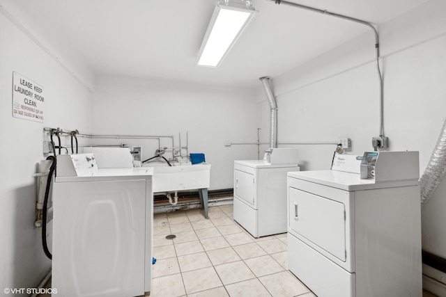 clothes washing area featuring light tile patterned floors, sink, and independent washer and dryer