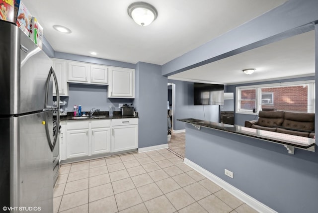 kitchen with white cabinets, sink, kitchen peninsula, stainless steel refrigerator, and light tile patterned floors