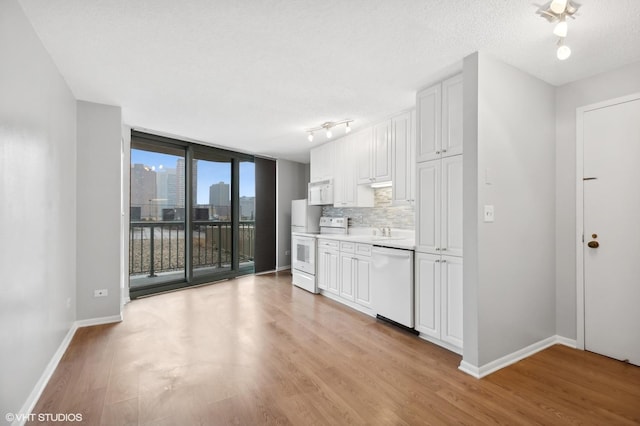 kitchen with white appliances, white cabinetry, tasteful backsplash, light hardwood / wood-style floors, and floor to ceiling windows