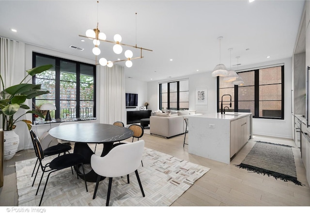 dining area featuring sink, a notable chandelier, and light wood-type flooring