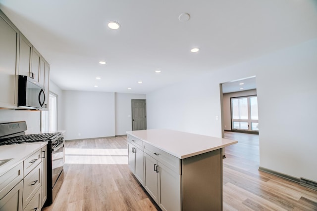 kitchen featuring light wood-type flooring, a kitchen island, range with gas cooktop, and gray cabinetry