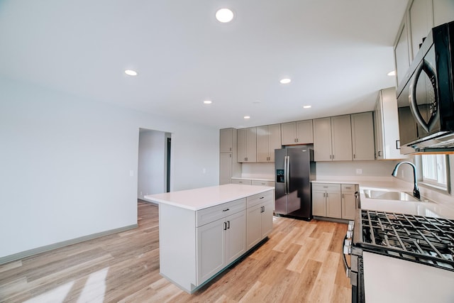 kitchen featuring gray cabinets, appliances with stainless steel finishes, sink, and a center island