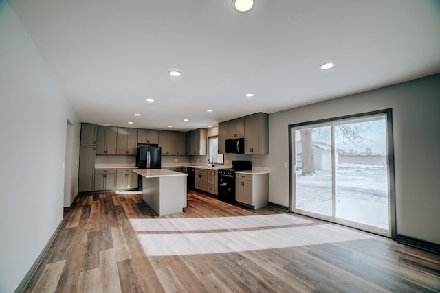 kitchen featuring gray cabinets, a healthy amount of sunlight, black appliances, and a center island