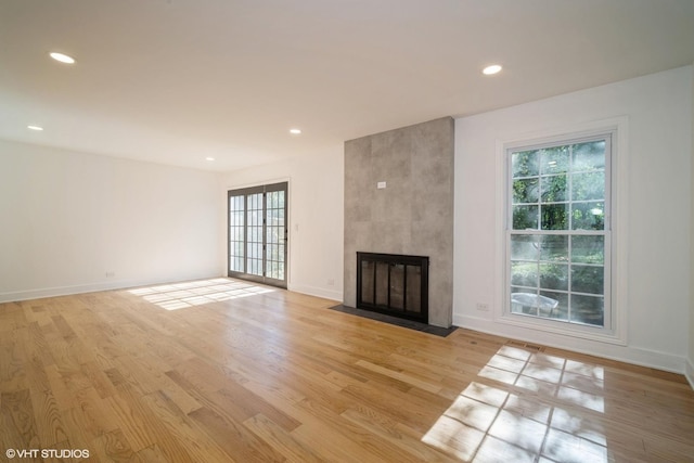 unfurnished living room featuring light hardwood / wood-style floors, plenty of natural light, and a large fireplace