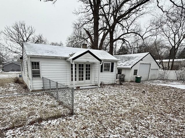 snow covered rear of property featuring a garage