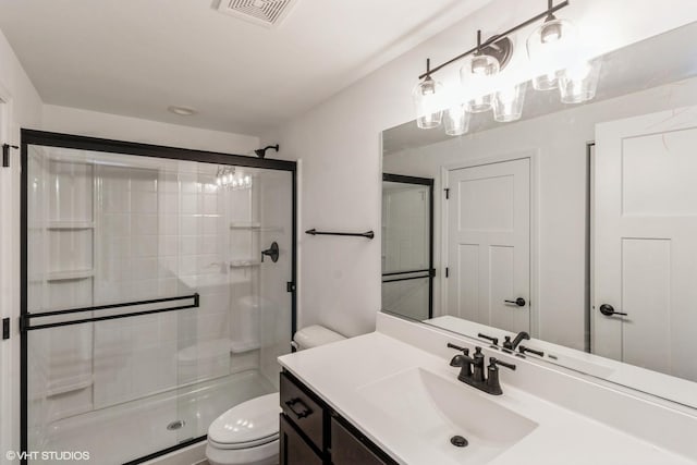 bathroom featuring toilet, a shower with shower door, and vanity