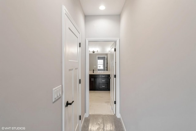 hallway featuring sink and light colored carpet