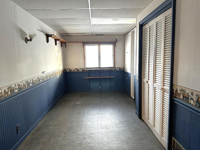 interior space with a drop ceiling and wood walls