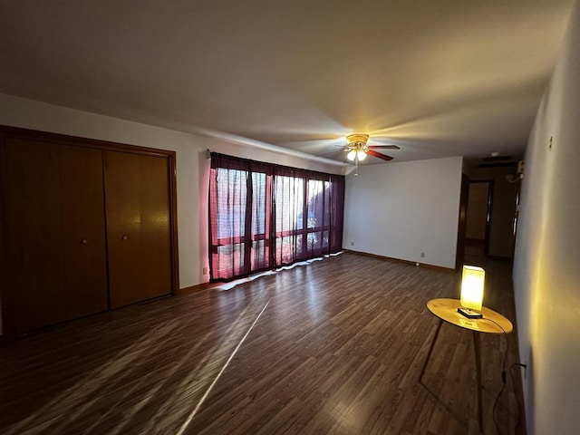unfurnished living room featuring dark wood-type flooring and ceiling fan