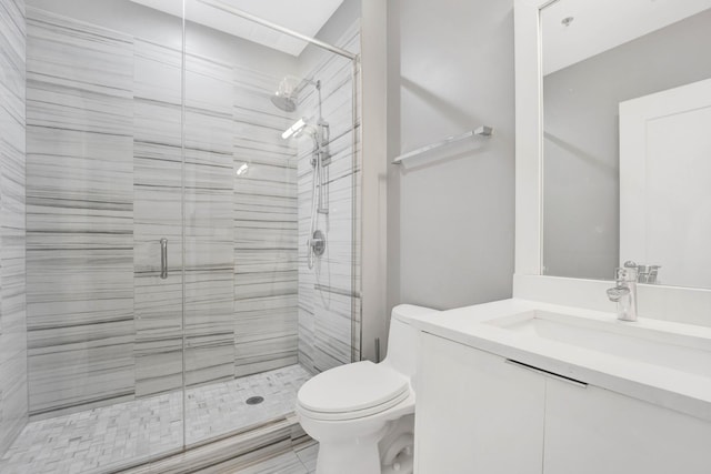 bathroom featuring a shower with door, toilet, and vanity