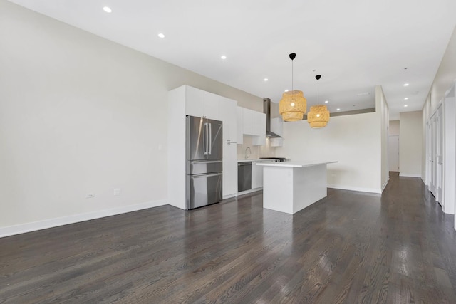 kitchen featuring stainless steel appliances, decorative light fixtures, wall chimney exhaust hood, white cabinets, and a center island