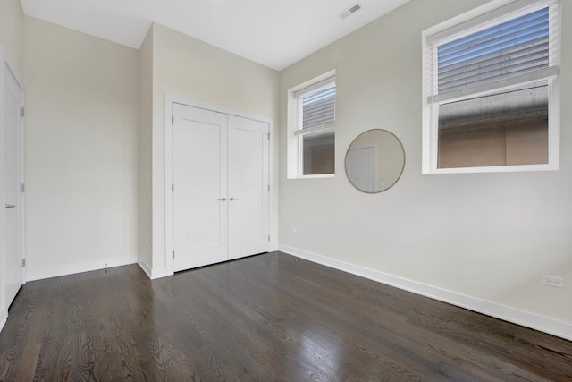 unfurnished bedroom featuring a closet and dark hardwood / wood-style flooring