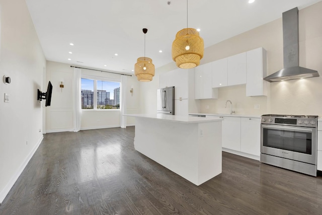 kitchen featuring wall chimney range hood, a center island, hanging light fixtures, appliances with stainless steel finishes, and white cabinets