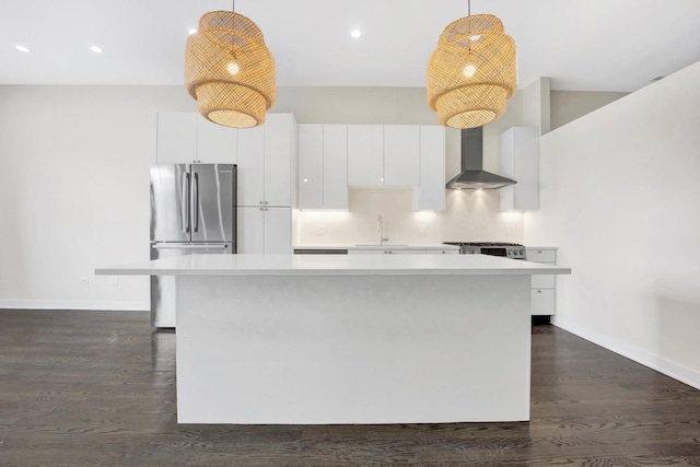 kitchen featuring white cabinets, stainless steel fridge, wall chimney exhaust hood, and pendant lighting