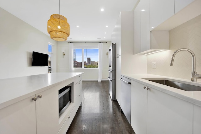 kitchen featuring stainless steel appliances, dark hardwood / wood-style flooring, pendant lighting, white cabinets, and sink