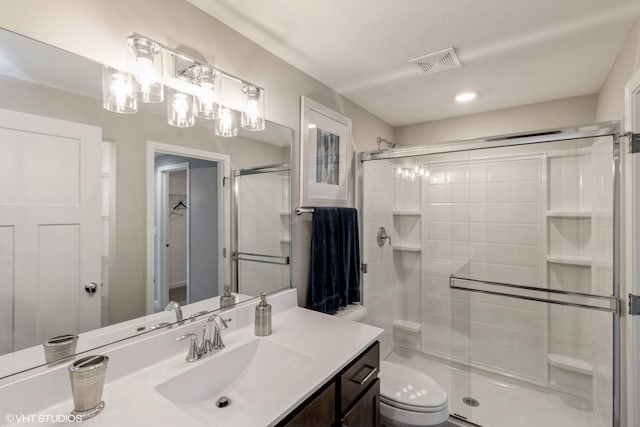 bathroom with a shower with shower door, toilet, and vanity