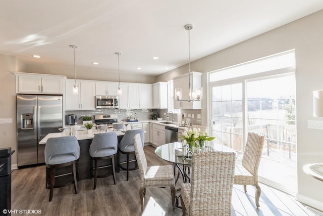 kitchen with sink, hanging light fixtures, white cabinets, and stainless steel appliances