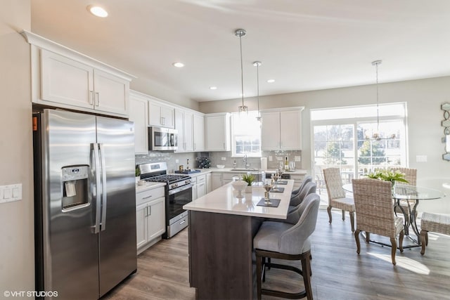 kitchen with stainless steel appliances, white cabinetry, and pendant lighting