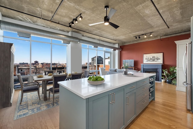 kitchen featuring light hardwood / wood-style flooring, stainless steel fridge, ceiling fan, gray cabinetry, and a center island