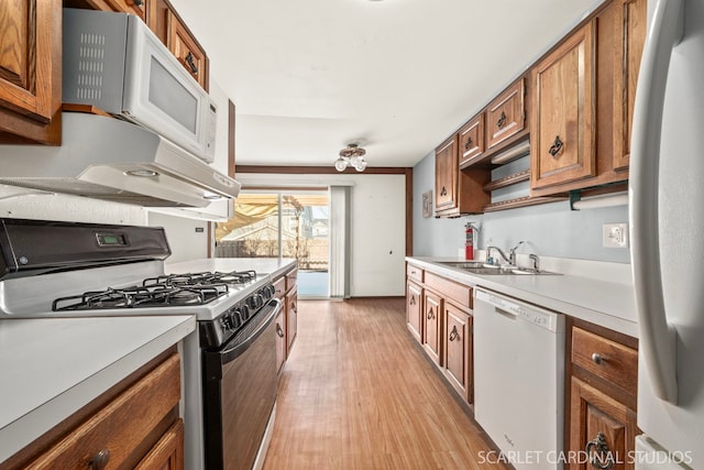 kitchen with white appliances, light hardwood / wood-style floors, and sink