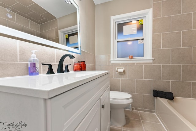 bathroom featuring toilet, tile patterned flooring, tile walls, a washtub, and vanity