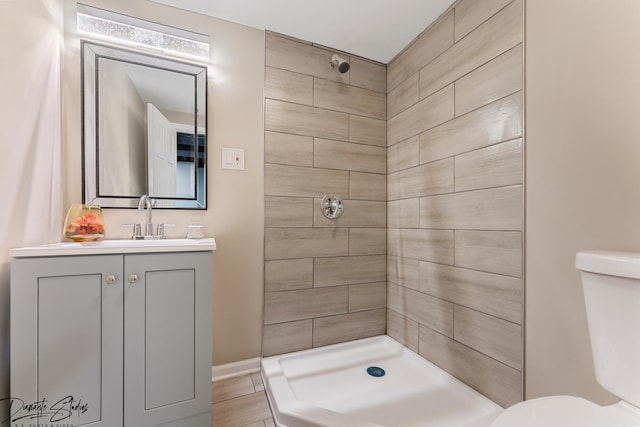 bathroom featuring tiled shower, vanity, and toilet