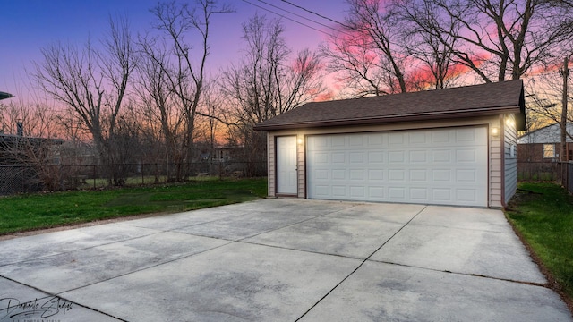 garage at dusk featuring a yard