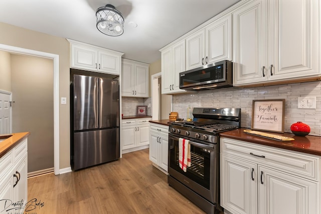 kitchen featuring decorative backsplash, white cabinetry, stainless steel appliances, and wooden counters