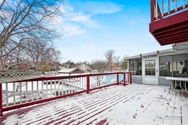 snow covered deck with a sunroom