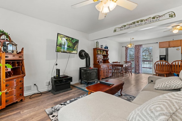 living room with ceiling fan, light hardwood / wood-style flooring, and a wood stove