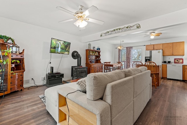 living room featuring ceiling fan, dark wood-type flooring, and a wood stove