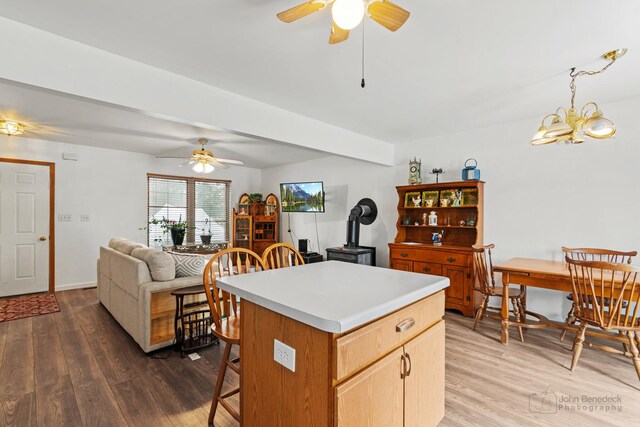 kitchen featuring a center island, beamed ceiling, pendant lighting, dark wood-type flooring, and ceiling fan with notable chandelier