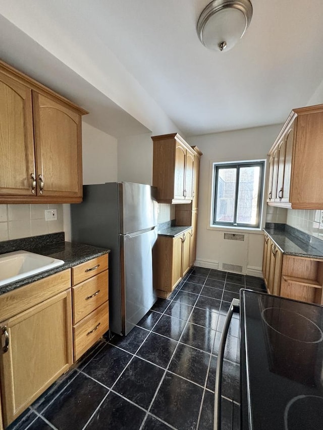 kitchen featuring sink, radiator, stainless steel refrigerator, and electric stove