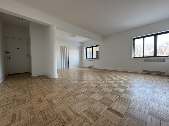 empty room with light parquet floors, radiator, and a wealth of natural light