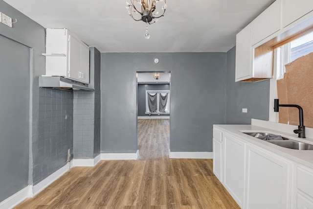 kitchen with sink, a chandelier, white cabinets, and light wood-type flooring