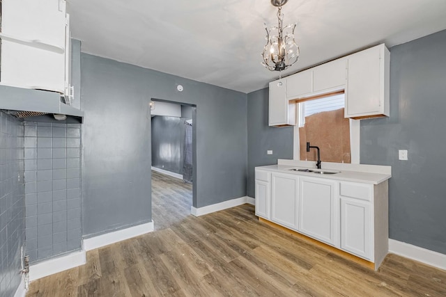 kitchen featuring sink, decorative light fixtures, a chandelier, light hardwood / wood-style flooring, and white cabinets