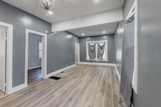 unfurnished room with light hardwood / wood-style floors and a chandelier