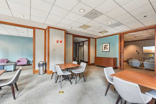 carpeted dining area featuring a paneled ceiling