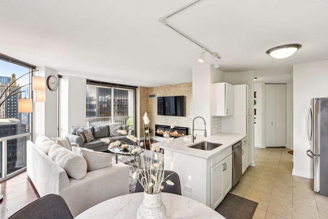 kitchen with white cabinets, light tile patterned floors, appliances with stainless steel finishes, decorative backsplash, and sink