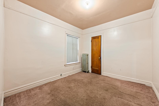 spare room with radiator and carpet