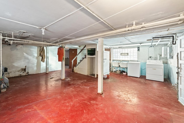 basement featuring sink, washer and clothes dryer, and electric panel