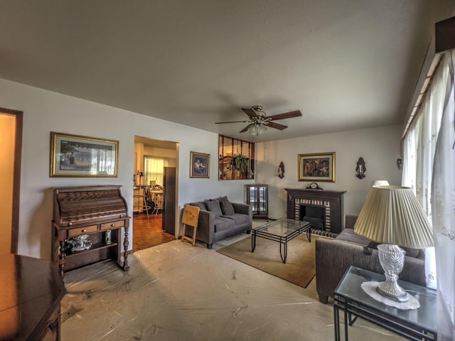 living room with a brick fireplace and ceiling fan